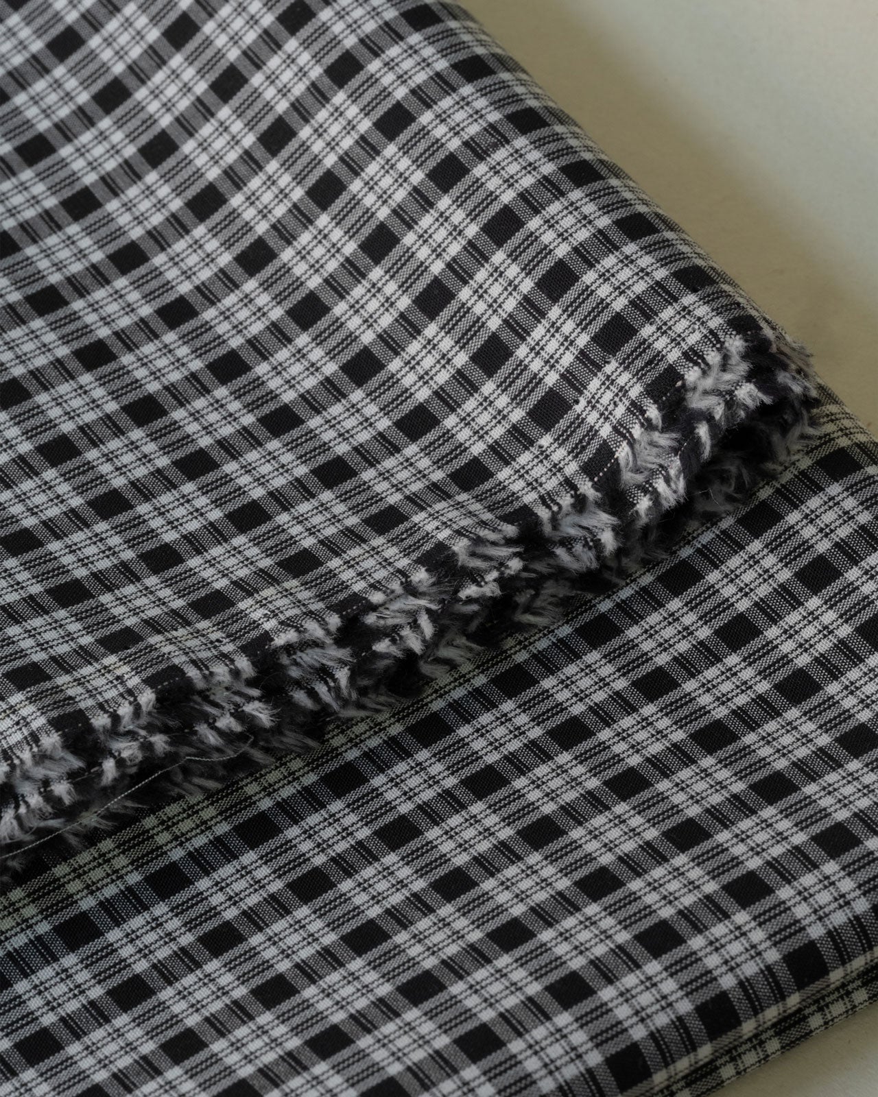 Close up image of black and white check deadstock cotton fabric for sewing home made clothes 