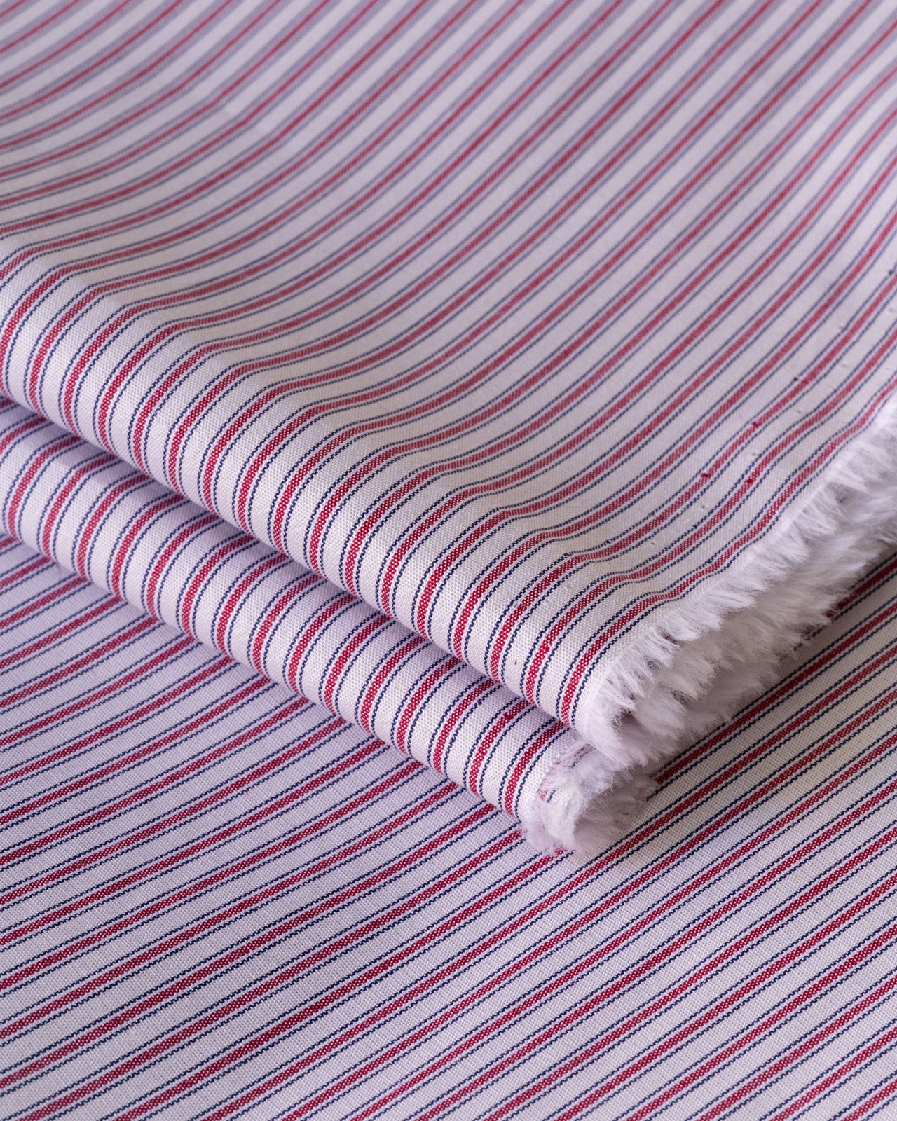 Close up image of red and white striped deadstock cotton fabric for sewing home made clothes 