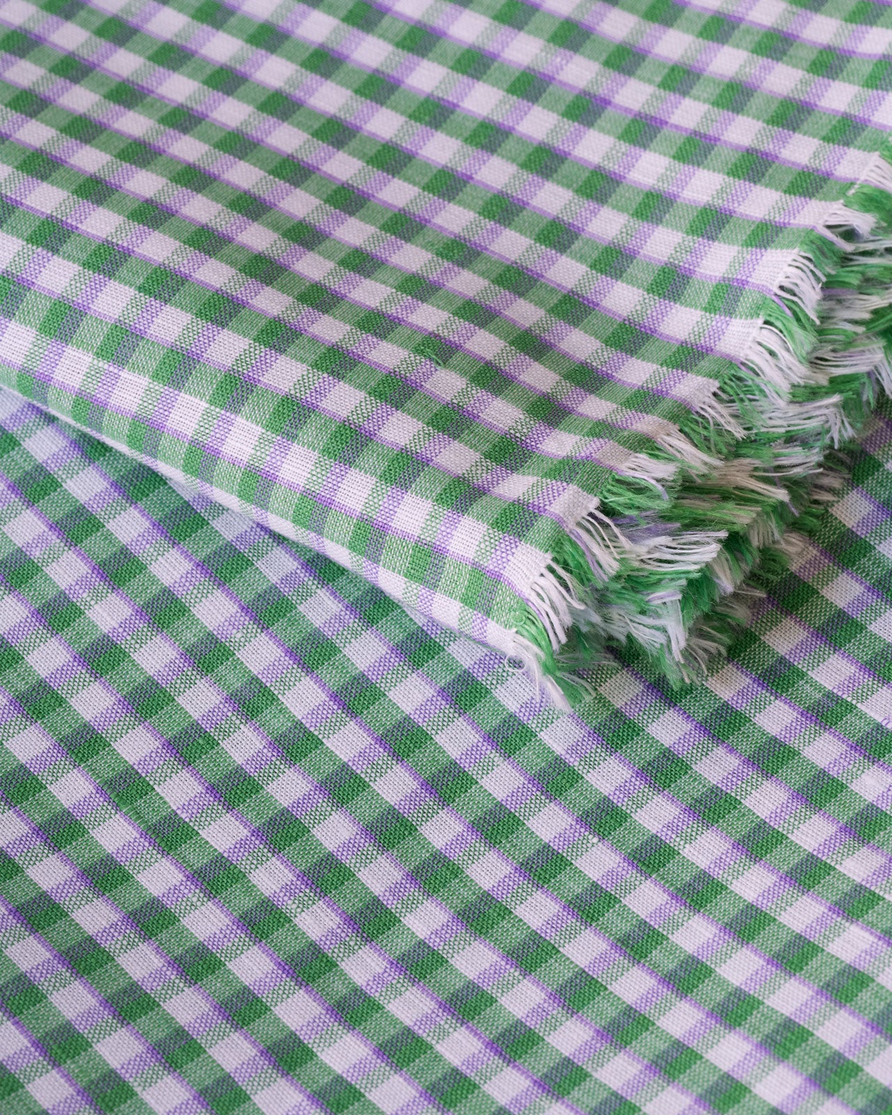 Close up image of green gingham deadstock linen cotton fabric for sewing home made clothes